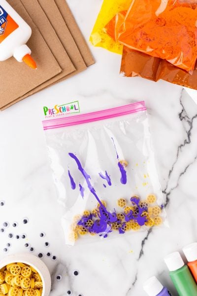 Simply combine rubbing alcohol and acrylic paint with your pasta in a ziplock bag. Seal it tightly and give it a good shake! Once the pasta is well-coated, spread it out on parchment paper to dry.