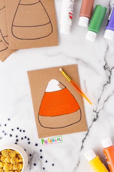 Before our class started, I sketched simple candy corn shapes on pieces of cardboard using a Sharpie. Depending on their age, some students might be ready to give this a try on their own—just remember to supervise those Sharpie markers closely!

Now comes the fun part: let your students unleash their creativity and paint their candy corn! They can stick to the classic white, orange, and yellow, or switch things up with autumn hues, apple shades, Frankenstein colors, or whatever wild ideas they come up with! We use paint trays to keep the mess minimal, so everyone can enjoy the process.